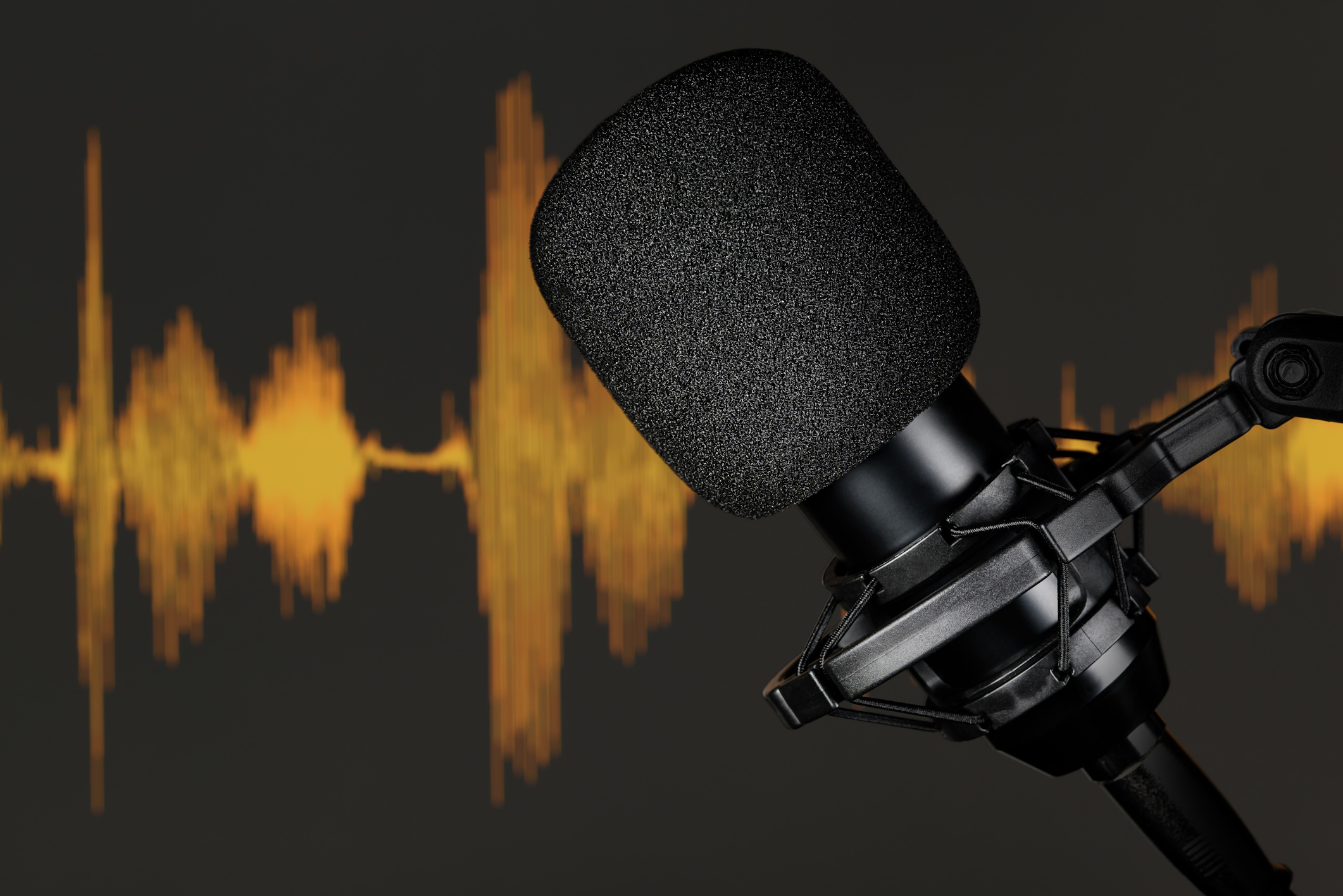 Close-up of a professional studio microphone against an orange audio waveform background, symbolizing the technical craft of podcast engagement strategies.