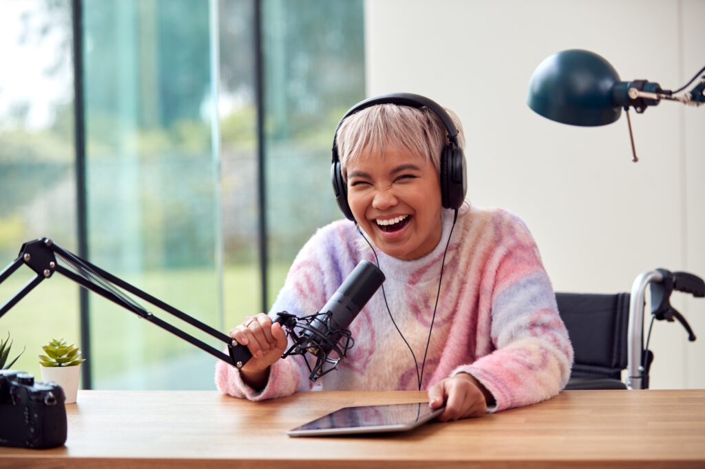 Podcaster in a striped sweater laughing joyfully while recording a podcast, embodying the essence of podcast audience engagement.